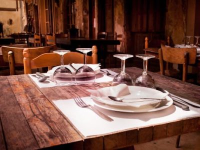 A rustic restaurant table set with wine glasses and cutlery invites guests to dine.