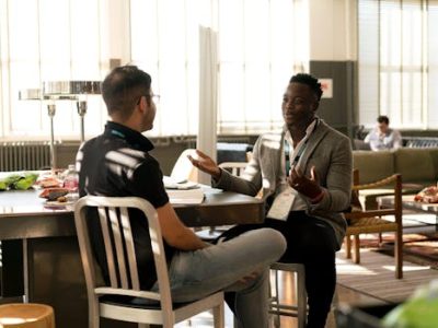 Two men having a casual discussion in a bright indoor setting, highlighting mentorship.